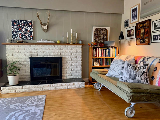 Furnished living room with a brick fireplace, hardwood floors, and a cozy bed. - 850 E 23rd Avenue, Vancouver East Side
