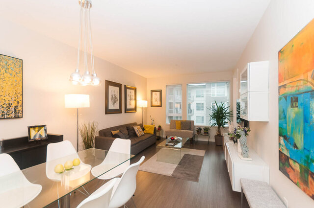 Modern living room with hardwood floors, contemporary furniture, and large windows offering city views. - 405 - 255 West 1st St, North Vancouver