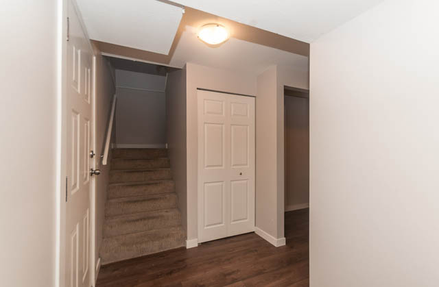 Bright hallway leading to stairs with hardwood floors and white walls. - 1528 Edgewater Lane, North Vancouver