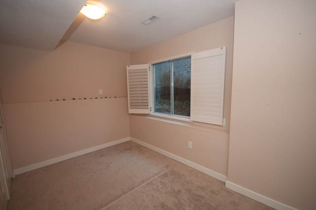Bright living room with sliding glass door leading to a patio, carpeted floors. - 1528 Edgewater Lane, North Vancouver