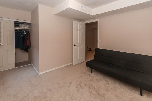 Furnished living room with a black couch and closet with hanging clothes. - 1528 Edgewater Lane, North Vancouver