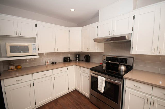 Bright kitchen with white cabinets, granite countertops, and hardwood floors. - 1528 Edgewater Lane, North Vancouver