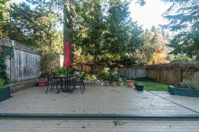 Furnished patio with wooden deck, greenery, and outdoor furniture. - 1528 Edgewater Lane, North Vancouver