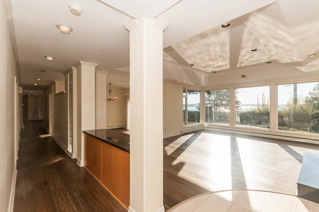 Bright living room with hardwood floors and large windows showcasing a city view. - 3399 Thompson Cres., West Vancouver