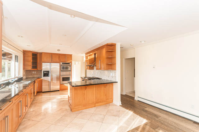 Bright kitchen with stainless steel appliances, granite countertops, and hardwood floors. - 3399 Thompson Cres., West Vancouver