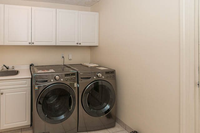 Bright laundry room with white cabinets and modern appliances. - 3399 Thompson Cres., West Vancouver