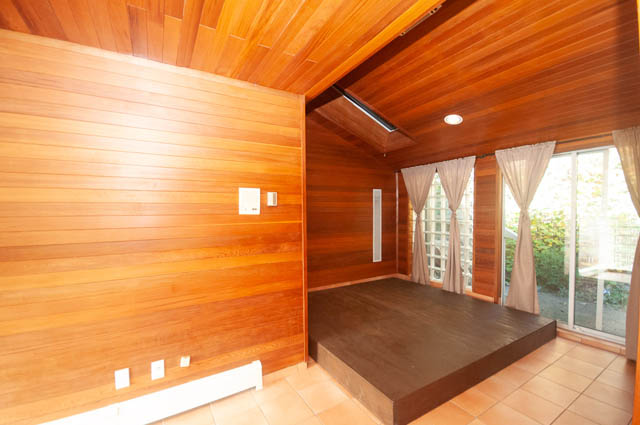 Bright living room with wooden walls and ceiling, large windows, and tiled floor. - 3399 Thompson Cres., West Vancouver