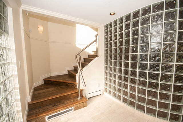 Staircase with glass block wall and wooden steps leading up. - 3399 Thompson Cres., West Vancouver