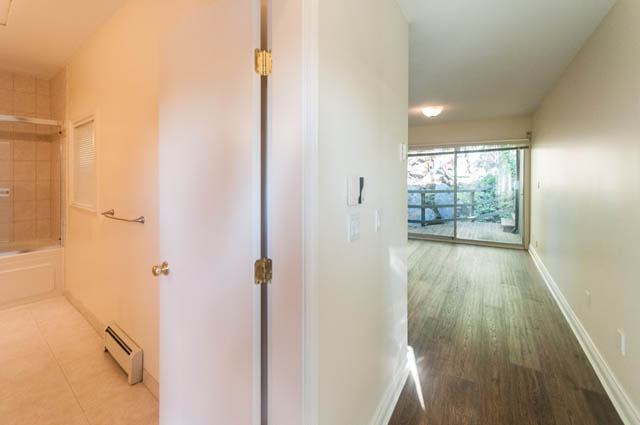 Bright bathroom with tiled walls and a shower, adjacent to a sliding glass door leading to an outdoor area. - 3399 Thompson Cres., West Vancouver