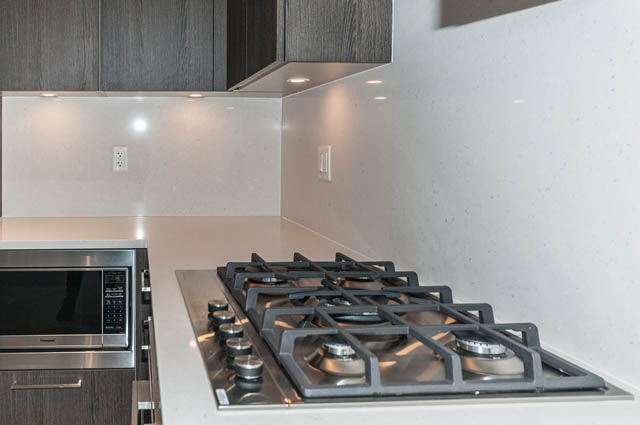 Bright kitchen with modern white countertops and stainless steel appliances. - 404 - 733 E 3rd St, North Vancouver