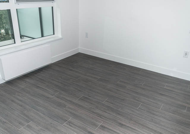 Bright living room with hardwood floors and a large window. - 404 - 733 E 3rd St, North Vancouver