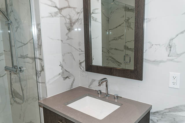 Bright bathroom with marble countertops and a modern shower setup. - 404 - 733 E 3rd St, North Vancouver