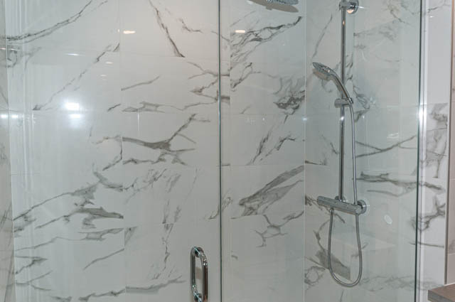 Bright bathroom with marble tiles and modern shower fixtures. - 404 - 733 E 3rd St, North Vancouver