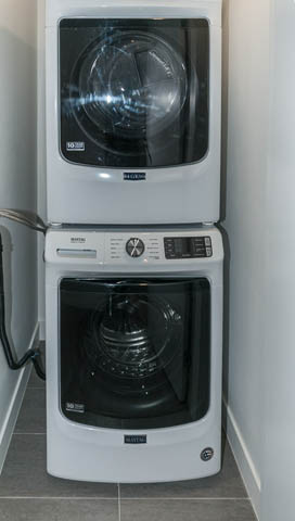 Bright laundry room with stacked washer and dryer, modern design. - 404 - 733 E 3rd St, North Vancouver