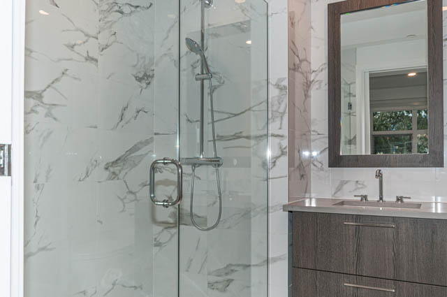 Bathroom with marble walls and a modern shower setup. - 404 - 733 E 3rd St, North Vancouver