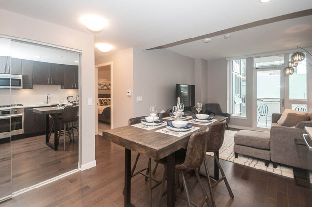 Spacious dining area with wooden table, modern chairs, and city view through sliding glass doors. - 401 - 1708 Ontario Street, Vancouver West Side