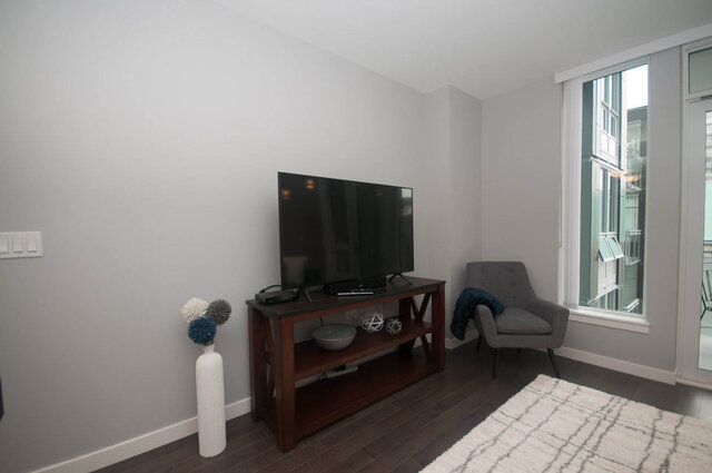 Modern living room with hardwood floors, a large TV, and a cozy corner chair. - 401 - 1708 Ontario Street, Vancouver West Side