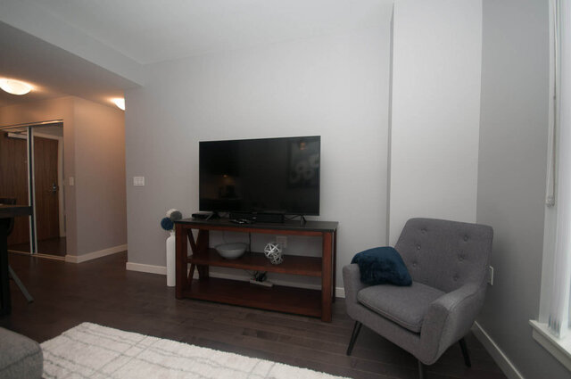 Spacious living room with hardwood floors, a large flat-screen TV, and modern furniture. - 401 - 1708 Ontario Street, Vancouver West Side
