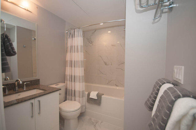 Spacious bathroom with marble tiles, modern shower, and granite countertop. - 401 - 1708 Ontario Street, Vancouver West Side