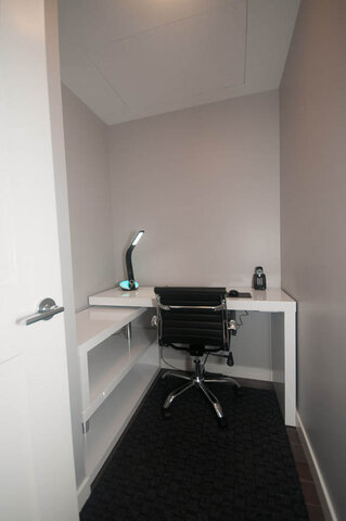 Compact home office with white desk, black office chair, and sleek desk lamp, perfect for a cozy workspace.