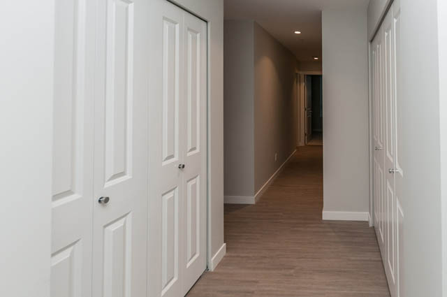 Bright hallway leading to a 3-bedroom condo with white doors and hardwood floors. - 404 - 2632 Library Lane, North Vancouver