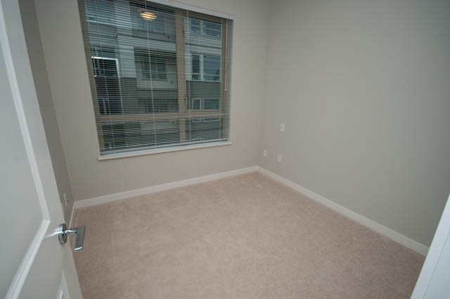 Bright living room with large window and carpeted floor. - 404 - 2632 Library Lane, North Vancouver