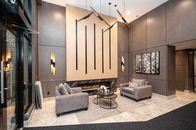 Spacious living room with modern lighting and plush seating. - 404 - 2632 Library Lane, North Vancouver