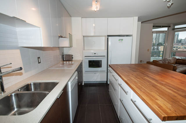 Bright kitchen with white cabinets, hardwood countertops, and city view. - 1001 - 175 West 2nd Street, North Vancouver