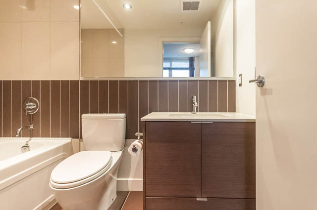 Furnished bathroom with modern sink, wooden cabinets, and large mirror. - 1001 - 175 West 2nd Street, North Vancouver