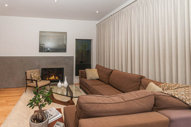 Spacious living room with hardwood floors, modern fireplace, and large windows. - 1964 W 15th Ave, Vancouver West Side