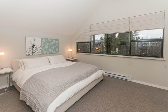 Spacious bedroom with large windows, city view, and cozy bedding. - 1964 W 15th Ave, Vancouver West Side
