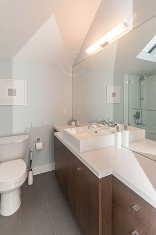 Bright bathroom with white countertop and modern sink, large mirror reflecting shower area. - 1964 W 15th Ave, Vancouver West Side