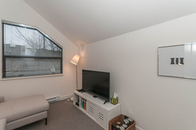 Bright living room with white walls, modern lighting, and a view of the city outside. - 1964 W 15th Ave, Vancouver West Side