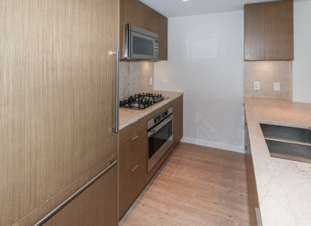 Bright kitchen with light wood cabinets, granite countertops, and stainless steel appliances. - 1001 - 125 E 14th St, North Vancouver