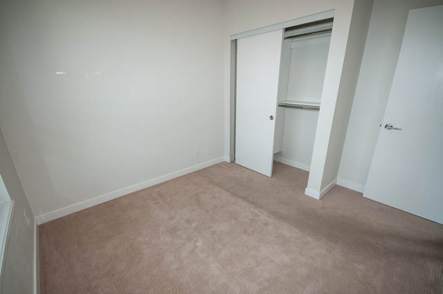 Bright bedroom with beige carpet and white closet doors. - 1001 - 125 E 14th St, North Vancouver
