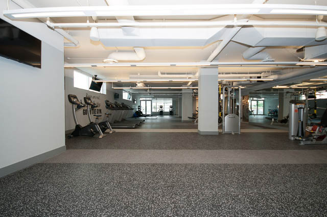 Furnished gym with cardio machines and mirrors, spacious layout. - 1001 - 125 E 14th St, North Vancouver