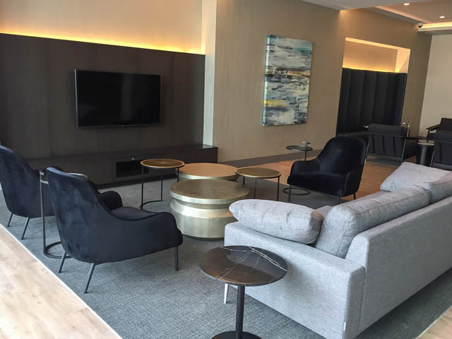 Furnished living room with modern furniture, large TV, and abstract wall art. - 1001 - 125 E 14th St, North Vancouver