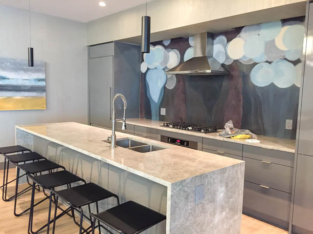 Bright kitchen with modern island, granite countertops, and abstract wall art. - 1001 - 125 E 14th St, North Vancouver