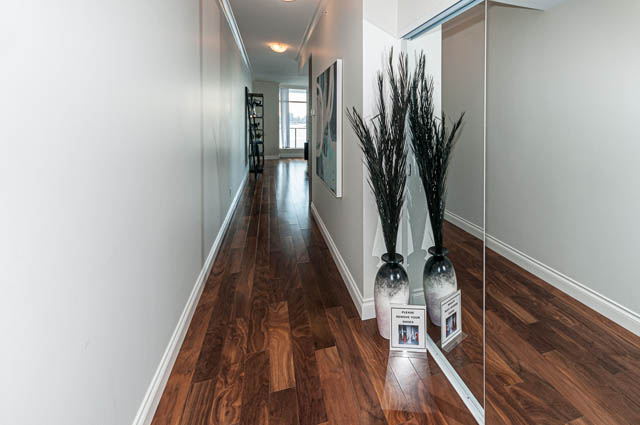 Furnished hallway with hardwood floors and wall art. - 702 - 185 Victory Ship Way, North Vancouver