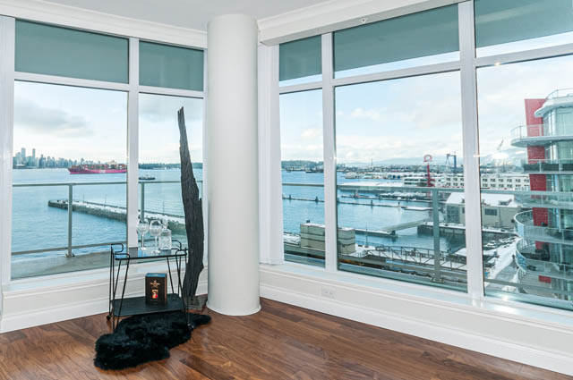 Bright living room with hardwood floors, city view, and large windows. - 702 - 185 Victory Ship Way, North Vancouver