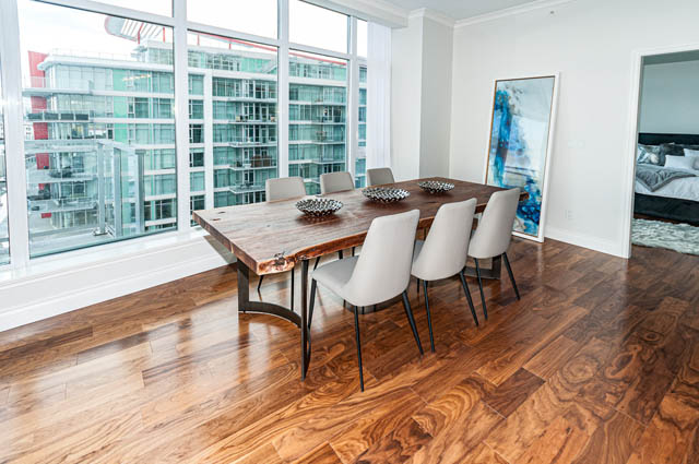 Bright dining area with hardwood floors, city view, and modern decor. - 702 - 185 Victory Ship Way, North Vancouver
