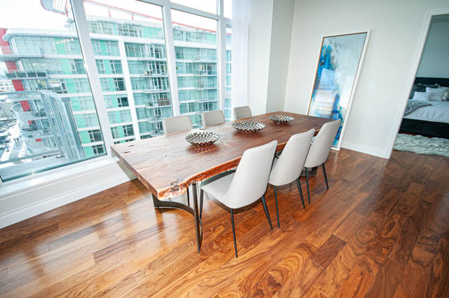 Spacious dining area with hardwood floors, city view, and modern decor. - 702 - 185 Victory Ship Way, North Vancouver