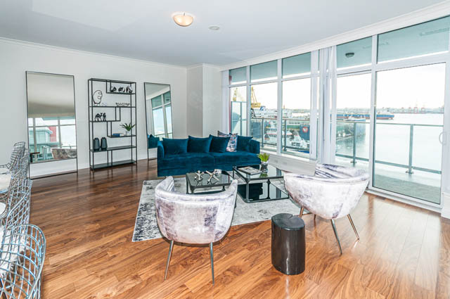 Spacious living room with hardwood floors, city view, and modern furnishings. - 702 - 185 Victory Ship Way, North Vancouver
