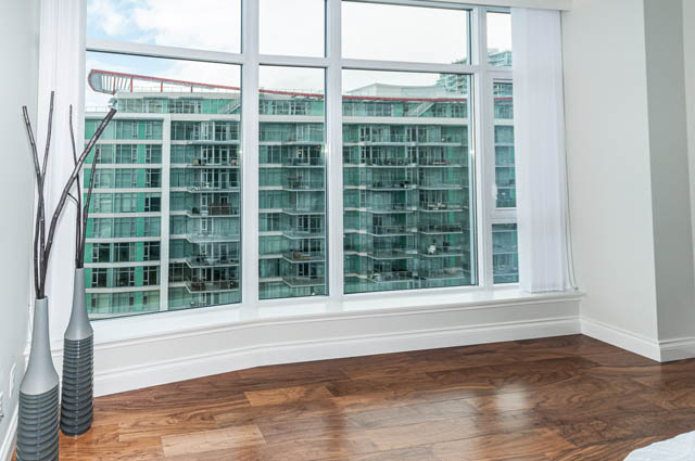 Bright living room with hardwood floors and city view. - 702 - 185 Victory Ship Way, North Vancouver