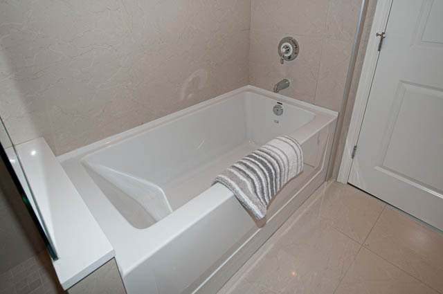 Bathroom with white bathtub, towel rack, and tiled walls. - 702 - 185 Victory Ship Way, North Vancouver