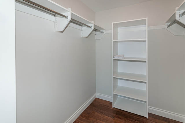 Bright walk-in closet with white shelving and hanging rods. - 702 - 185 Victory Ship Way, North Vancouver
