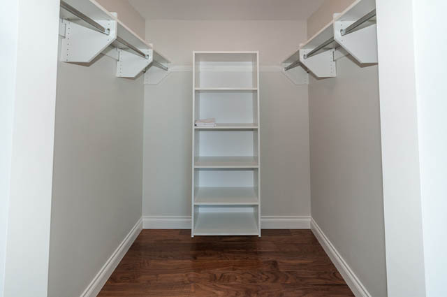 Furnished walk-in closet with built-in shelves and hardwood flooring. - 702 - 185 Victory Ship Way, North Vancouver