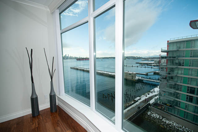 Bright living room with hardwood floors and a stunning city view. - 702 - 185 Victory Ship Way, North Vancouver