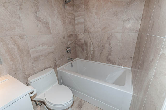 Furnished bathroom with marble tiles and a bathtub. - 702 - 185 Victory Ship Way, North Vancouver