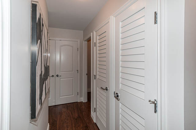 Furnished hallway with white closet doors and hardwood floors. - 702 - 185 Victory Ship Way, North Vancouver